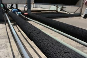 Black foam pipe insulation covering a pipe on a concrete floor. Best pipe insulation for homes and businesses helps prevent frozen pipes and heat loss.
