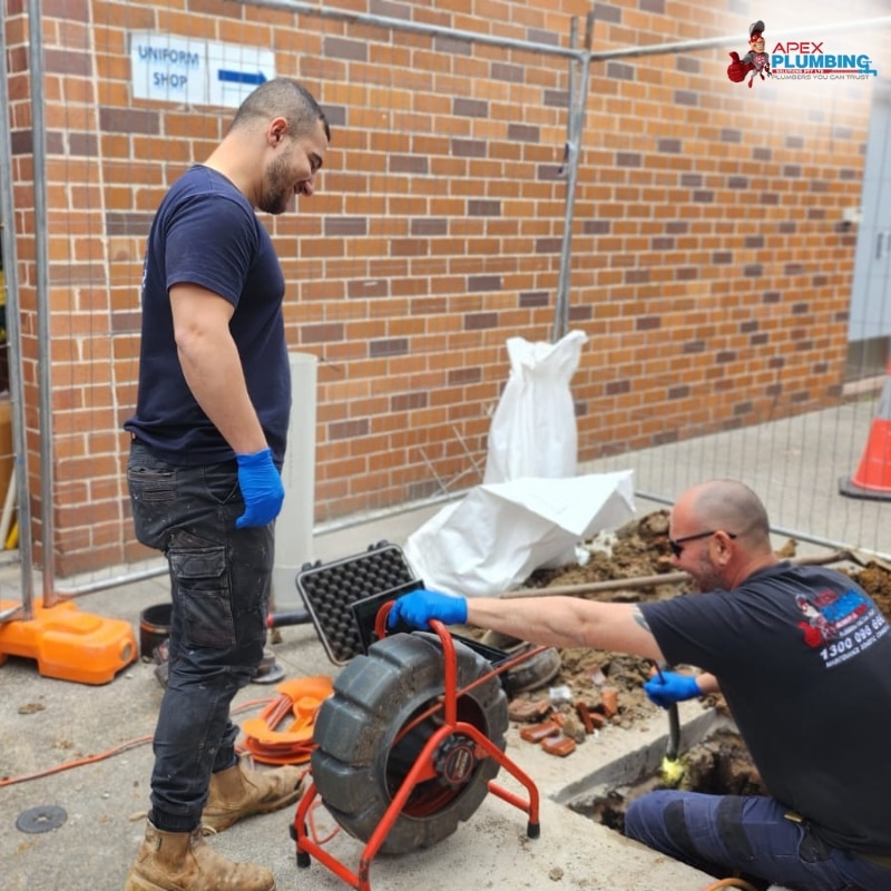 Two blocked drain plumbers fixing a clogged drains